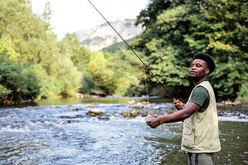 African American fisherman enjoys fishing on a mountain river