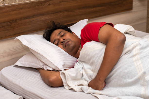 istock Side view of clean shaved Indian man sleeping on bed in bedroom. 1700536311