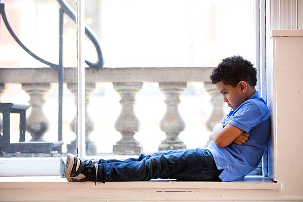 Pouting boy A young boy sits in a window pouting puckering stock pictures, royalty-free photos & images