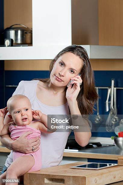 Multitareas Mujer En El Teléfono Retención De Niña Bebé En La Cocina Foto de stock y más banco de imágenes de 30-34 años