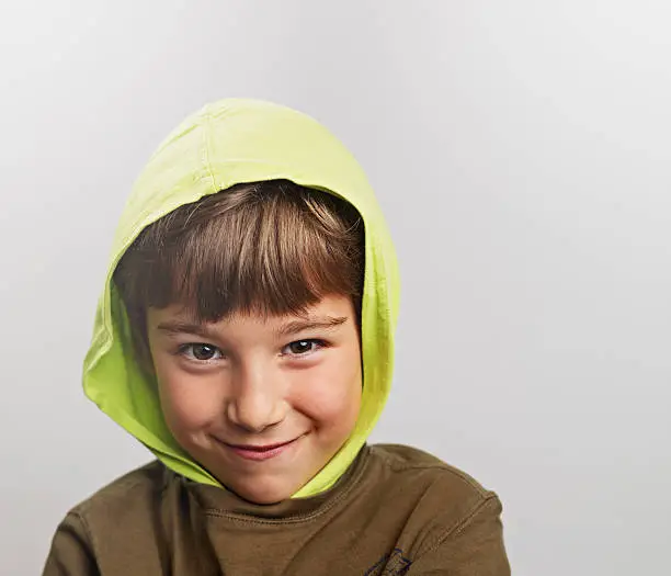 Mischievous child smiling with a hood.