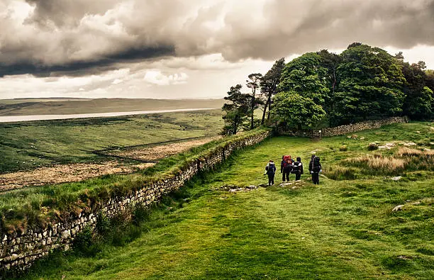 A group of hikers walk along Hadrian's Wall in Northern England.  With dramatic processing.