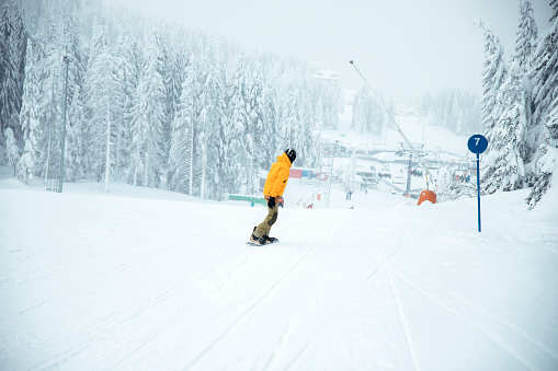 Man Snowboarding in ski resort during foggy day