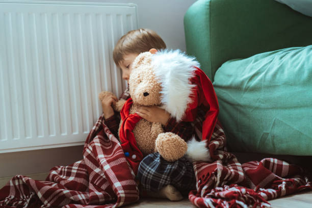 istock cute little boy wrapped id plaid sitting by heater 1700565412