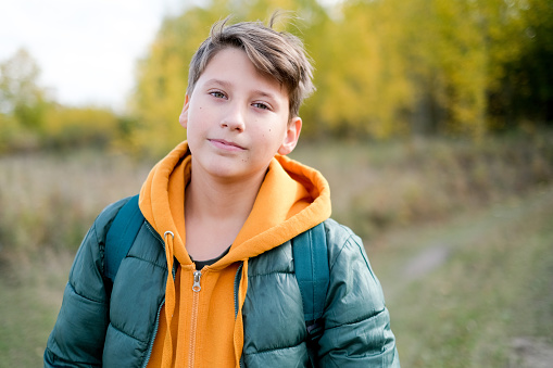Portrait cheerful teen walking school at autumn. Boy is in a yellow looking camera