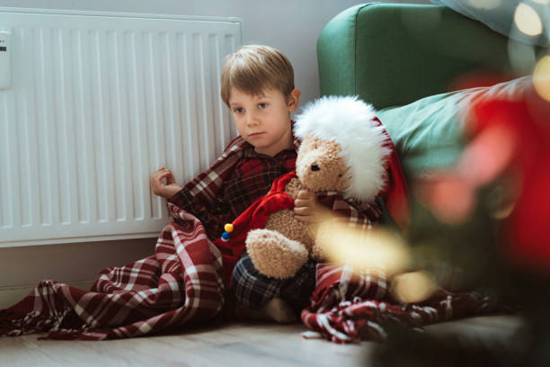 istock cute little boy wrapped id plaid sitting by heater 1700566071