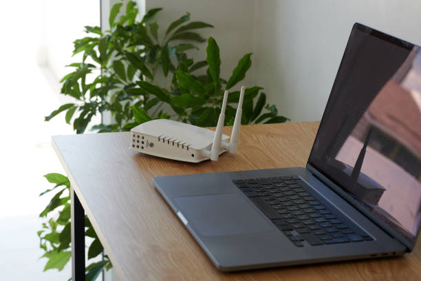 Wifi Router and Laptop on Desk Wifi router and laptop on desk on freelancer working from home router stock pictures, royalty-free photos & images