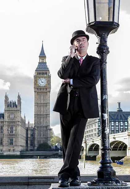 Young stockbroker speaking for telephone  next to the Westminster Bridge and Big ben in the background