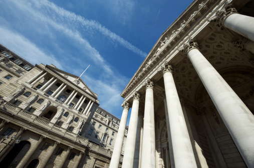 Bank of England building stands under blue sky next to soaring columns