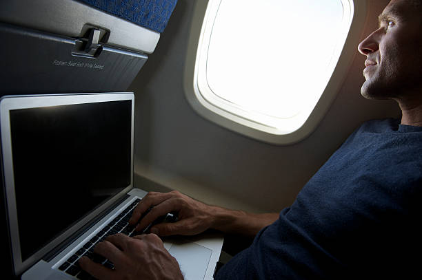 istock Traveling Man Looks Out Airplane Window Using Laptop 170058830