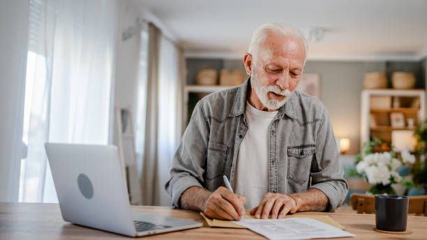 istock senior caucasian man open mail letter sign contract document at home 1700589582
