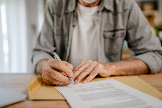 istock senior caucasian man open mail letter sign contract document at home 1700589604