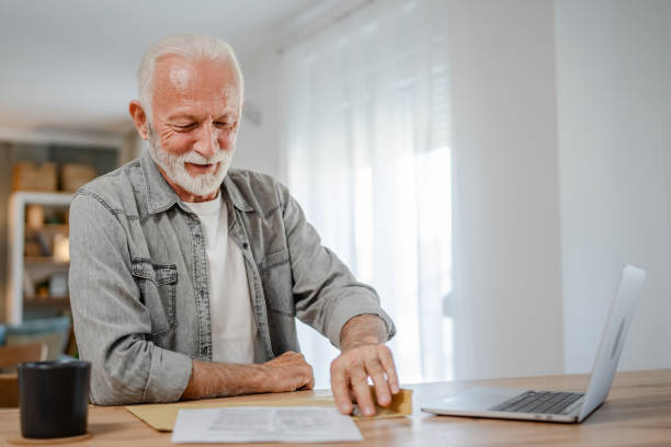 istock senior caucasian man open mail letter sign contract document at home 1700590414