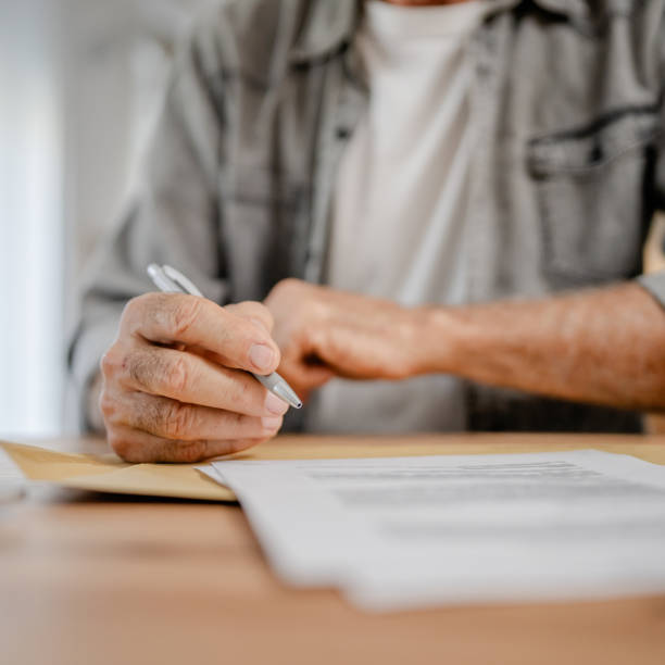 istock senior caucasian man open mail letter sign contract document at home 1700590645