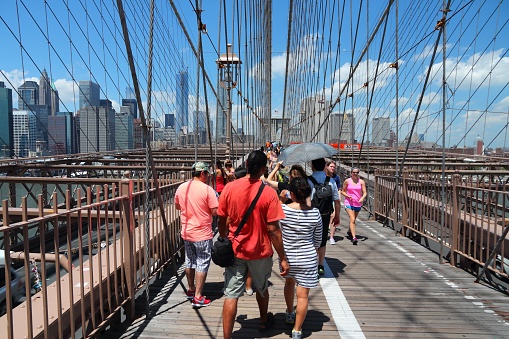 People walk across famous Brooklyn Bridge in New York. Almost 19 million people live in New York City metropolitan area.