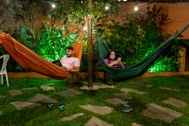 istock Young couple relaxing on hammocks in backyard at night 1700600142