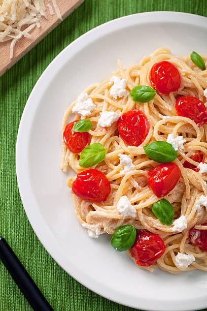 Spaghetti with cherry tomatoes and ricotta Spaghetti with cherry tomatoes and ricotta cooked selective focus vertical pasta stock pictures, royalty-free photos & images