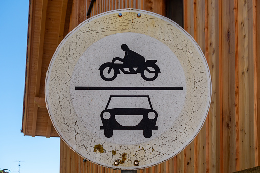 Passage for cars and motorcycles prohibited. Old german traffic sign, made of sheet metal, in a small village in Upper Bavaria, Bavaria, Germany. The colors of the traffic sign are already faded by the sun and the weather conditions. The sign ( Number 252 ) was published in 1970. The sign is still valid.