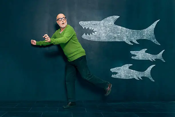 Terrified man escaping from wild sharks.