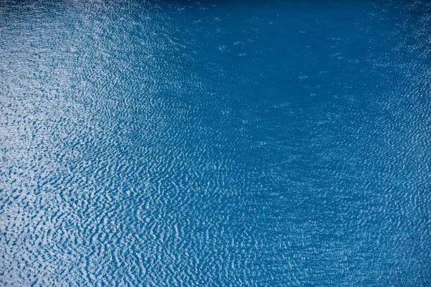 istock Water with small waves and raindrops on a pool with blue texture background 1700611579