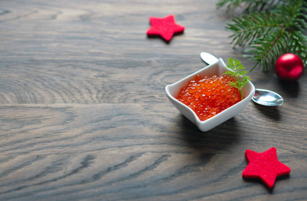 Salmon Red Caviar in bowl and Christmas decorations on wooden background. stock photo
