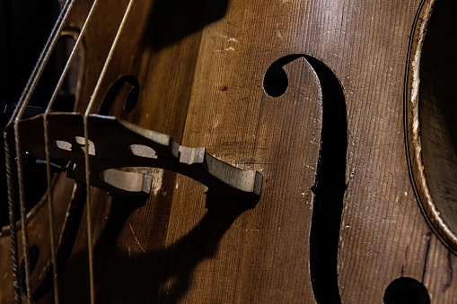 Close-up of vintage and well-worn cello or bass fiddle acoustic instrument with dramatic lighting