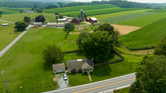 An Aerial View, in Late Afternoon, of Farmlands, Corn Fields, Harvested Fields, Silos, Barns and Rural Road, Summer Day