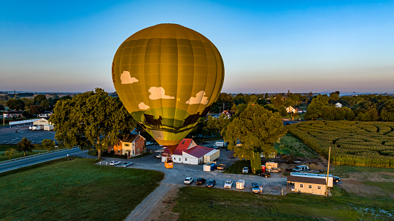 An Aerial View of a Golden Hot Air Balloon, Just Launched and Floating Across a Field on a Sunny Summer Morning