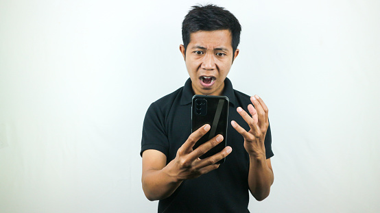 Disappointed, not expect, angry expression of asian man reading bad news at mobile phone isolated on white background.