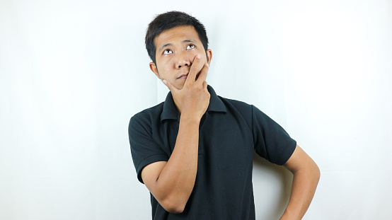 expression of asian man wearing black t-shirt hand on chin thinking, thinking about something.