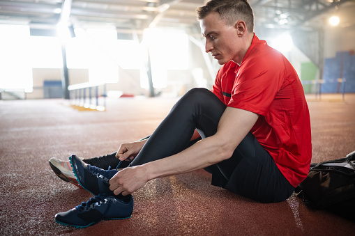 Athlete tying his sport shoelace for better and safety training. Sport and Healthy lifestyle concept.