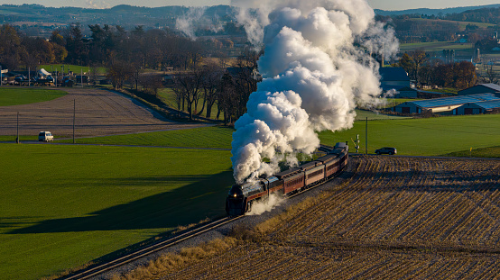 An Aerial View at Sunrise of a Steam Passenger Train Approaching Blowing A Lot of Smoke on a Autumn Day