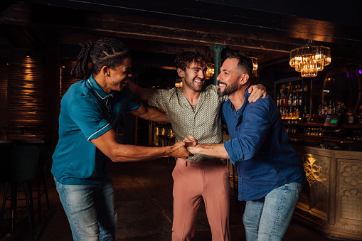 Group of male friends celebrating New Year together at a party in the North East of England. They are having fun dressed fashionably picking each other up while they laugh.