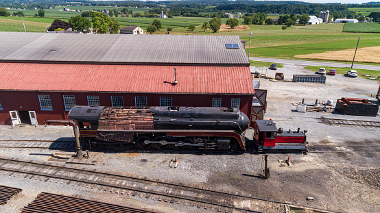 Staunton, United States – October 06, 2023: An old-fashioned steam train chugging through a lush, green forest, surrounded by tall trees