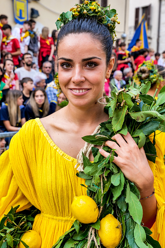 Gualdo Tadino, Umbria, Italy, September 22 -- A beautiful woman wears a yellow medieval dress during a historical reenactment in the small town of Gualdo Tadino in Umbria, central Italy. The Umbria region, considered the green lung of Italy for its wooded mountains, is characterized by a perfect integration between nature and the presence of man, in a context of environmental sustainability and healthy life. In addition to its immense artistic and historical and medieval heritage, Umbria is famous for its food and wine production and for the high quality of the olive oil produced in these lands. Image in high definition quality.