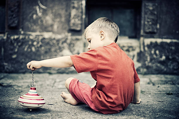 enfant jouant avec un haut de spinning - street child photos et images de collection