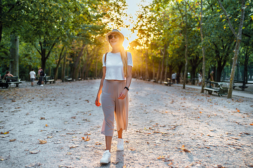Young cheerful woman walking through the park during a beautiful day