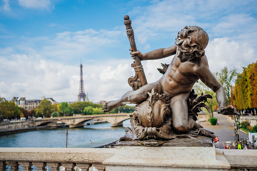 Ornate stone statue on the Pont Alexandre III bridge and the Eiffel Tower in the background, Paris, France