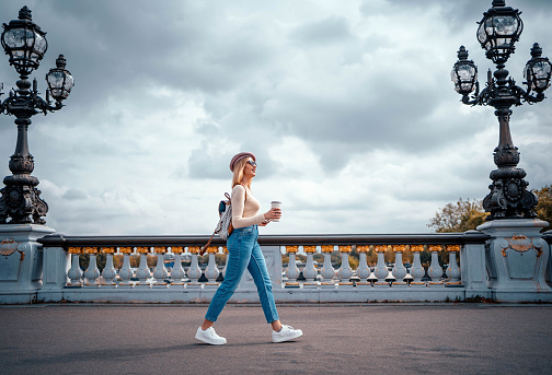 Young cheerful woman walking on Pont Alexandre III bridge in Paris, France