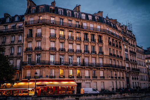 Street view of the elegant facade of an old apartment building in a residential neighborhood of Paris, France at night