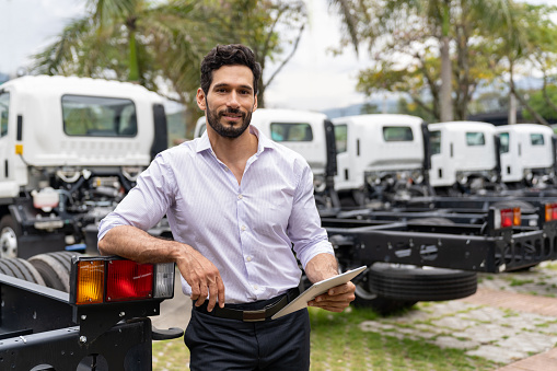 Portrait of a Latin American man selling trucks at a car dealership - sales occupation concepts