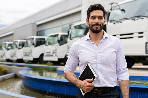 Portrait of a Latin American car salesperson working at the dealership selling trucks - business concepts
