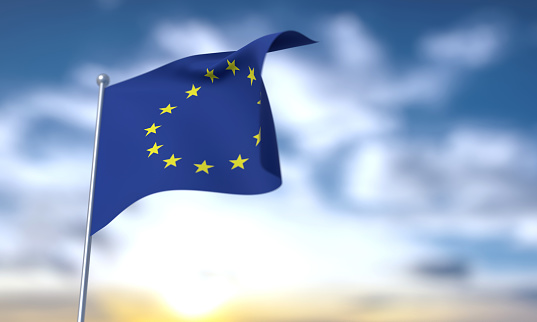The European flag fluttering in the wind with a blue sky background.