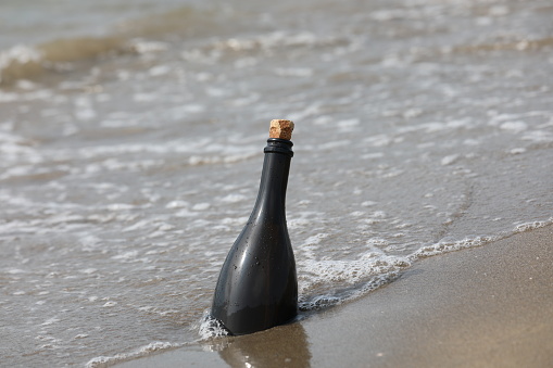 Dark Green Glass bottle on beach with a secret message inside