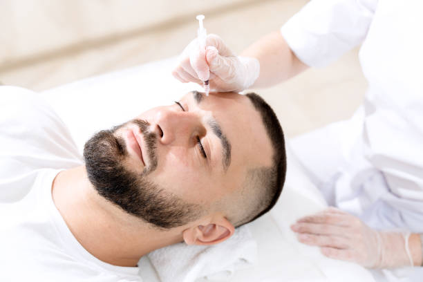 istock Botulinum injection in cosmetology clinic for handsome man. Method of wrinkle correction by local injection. Smoothing forehead wrinkles in the brow area. 1700778839