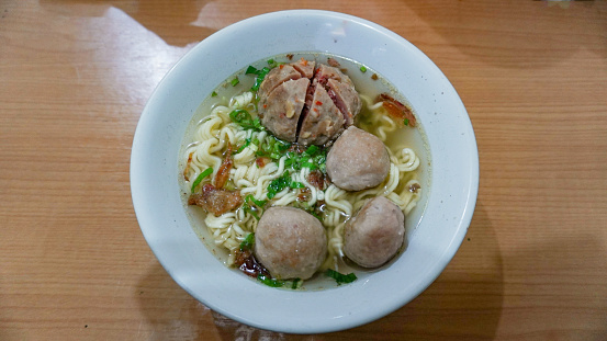 Indonesian meatball or called baso, served with soup, celery, fried union and noodles. Top view