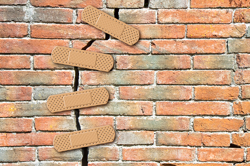 Renovation of an old cracked brick wall - concept with bandaid patch