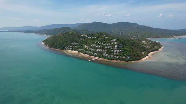 Koh Samui Thailand Island Luxury Resort overlooking ocean, Aerial view pull back with blue water and blue skies