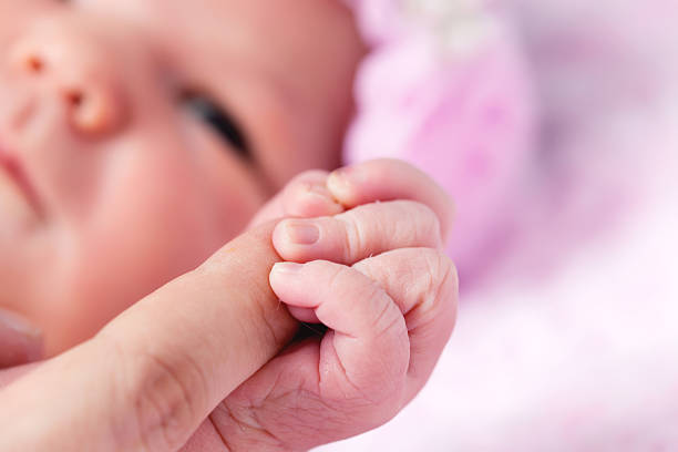 Newborn baby girl holding mothers hand stock photo