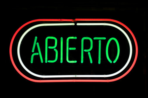 Abierto (Spanish for open) message in green neon is encircled by two more bands of neon against black background